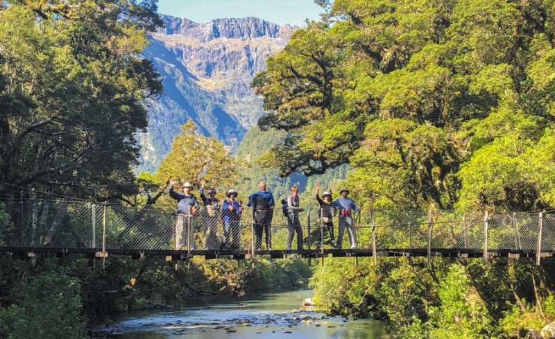 Group of guests waving from bridge milford track best guided tours blog