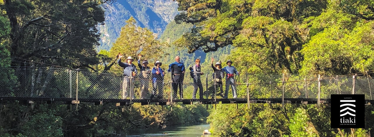 Header Image guests waving from bridge milford track