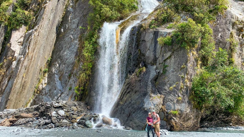 smiling couple in front of waterfall firodland web