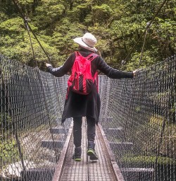 Lady on the bridge at Milford Track, Arthur river, Fiordland New Zealand