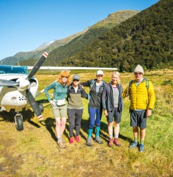 Five happy guests next to bush plane Siberia Valley