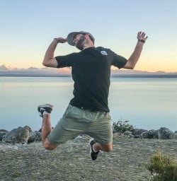 Guide jumping at Lake Pukaki with Aoraki Mt Cook in the background, Canterbury New Zealand
