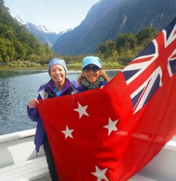 hikers holding new zealand flag at milford sound