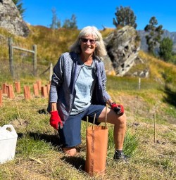 Guest kneeling planting trees in Arrowtown 060125
