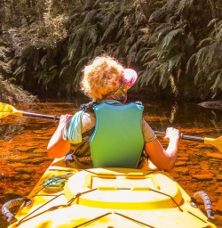 Lady kayaking at Okarito Lagoon, West Coast New Zealand