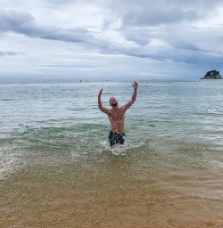Guide having a swim at Kaikeriteri at Abel Tasman National Park, New Zealand